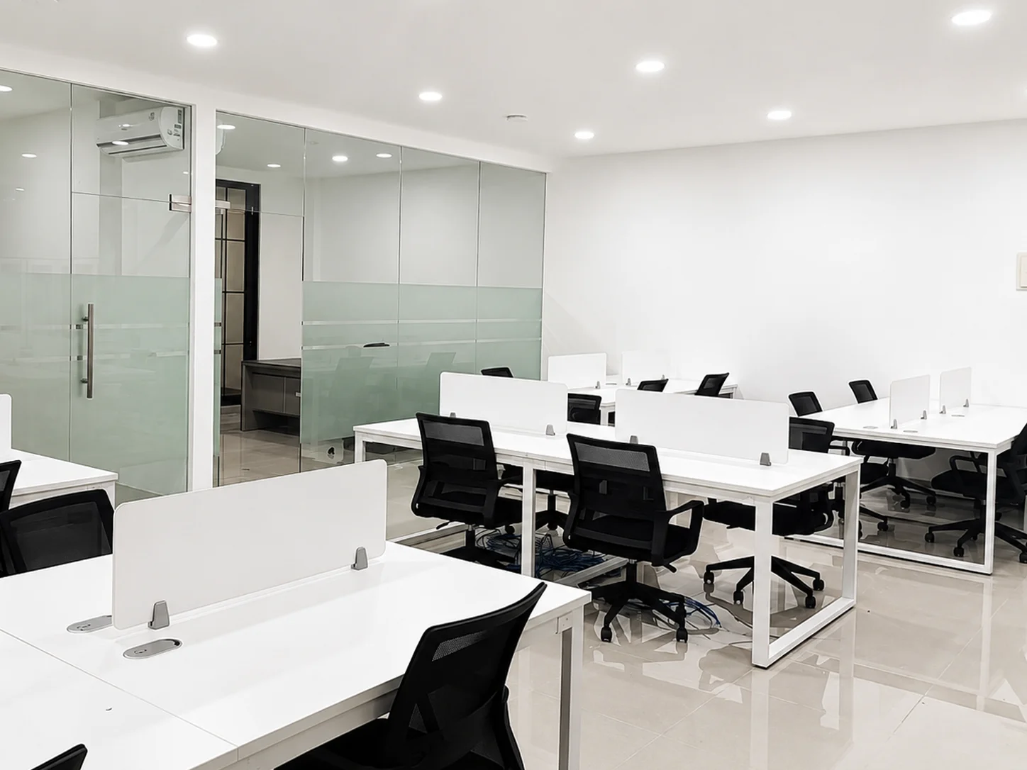 Penataan workstation kantor putih dengan kursi kerja dan ruang partisi kaca
