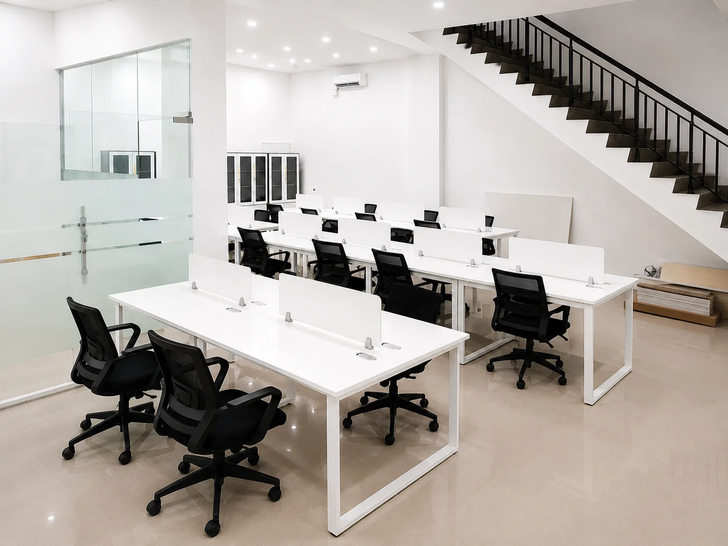 Area kantor modern dengan workstation putih dan kursi kerja di ruang kerja terbuka